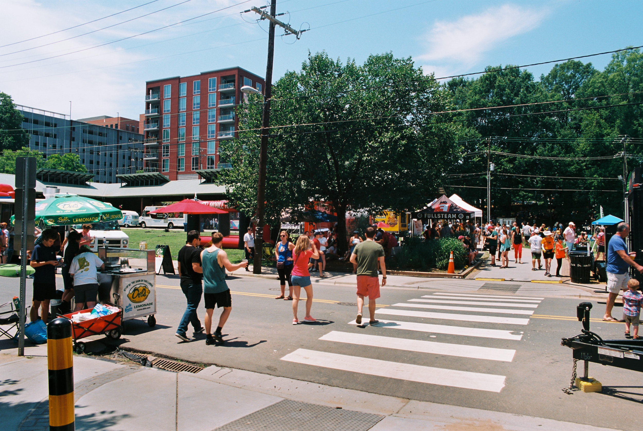 Sunny day in downtown Durham with residents and visitors visiting food and craft stands lining the streets.